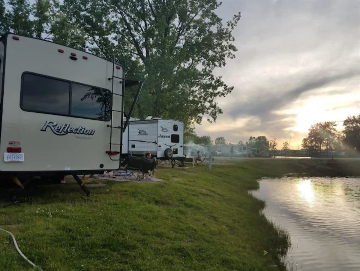 An RV parked at the water's edge at sunset, Krystal Lake Family Campground